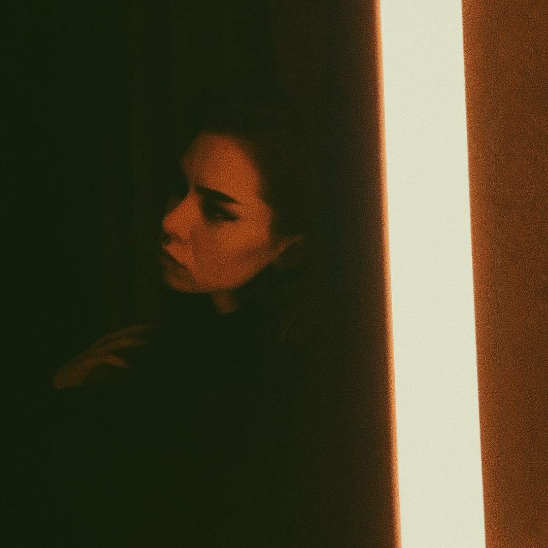 Forlorn woman leaning against a door frame