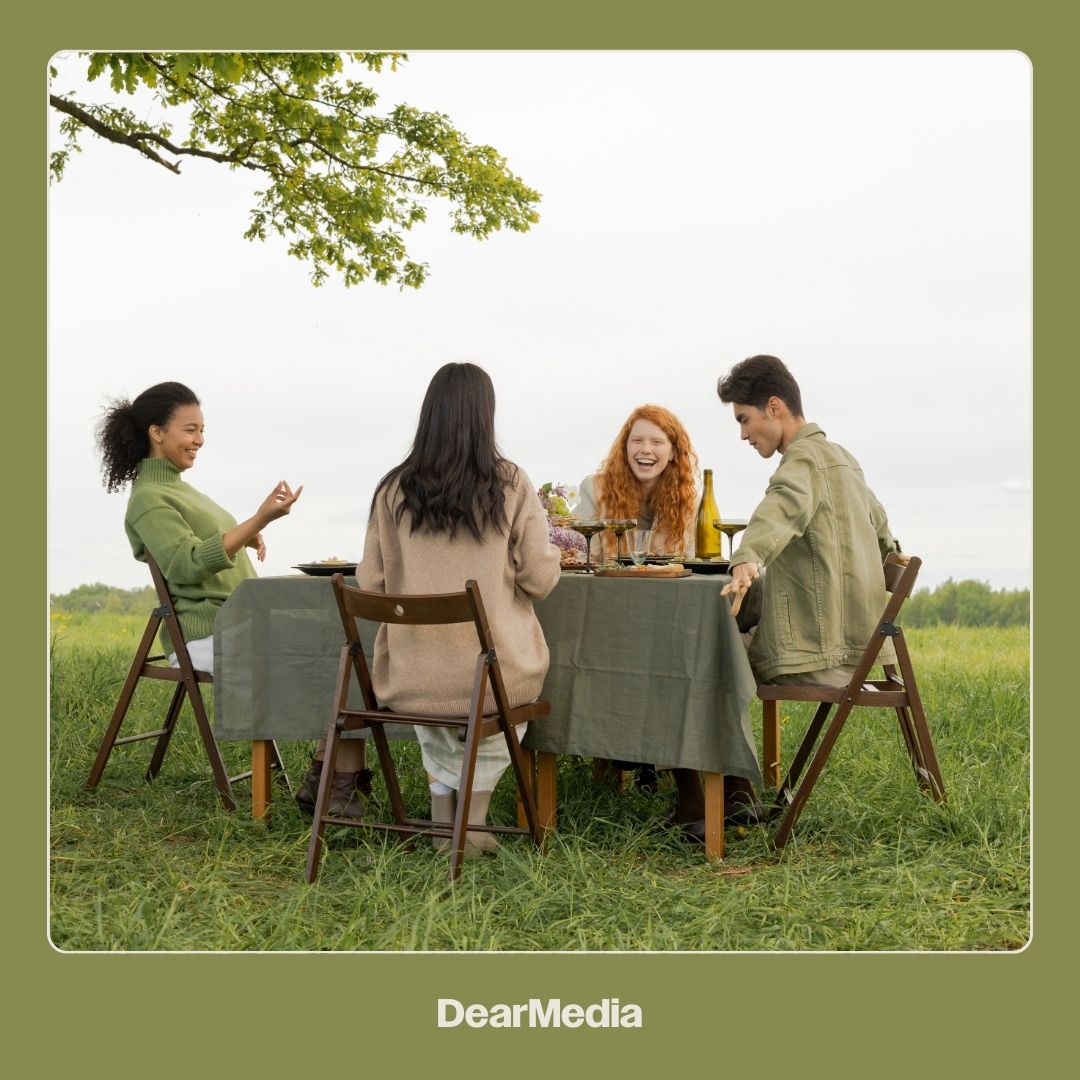 Group of friends talking at a table in a meadow